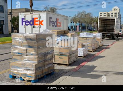 Galveston, Texas - Februar 2023: Güterpaletten am Straßenrand mit einem Federal Express FedEx-Lkw im Hintergrund Stockfoto