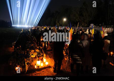 Lemberg, Ukraine 23. februar 2023. Familienmitglieder besuchen die Gräber gefallener Soldaten auf dem Friedhof Lychakiv, wo Hunderte ukrainischer Soldaten, die im letzten Jahr gestorben sind, bei einer Gedenkveranstaltung begraben werden, als symbolische „Strahlen der Erinnerung“ auf dem Militärfriedhof Lychakiv anlässlich des ersten Jahrestages des Bestehens von angezündet wurden Russlands Krieg gegen die Ukraine. Russland marschierte am 24. Februar 2022 in die Ukraine ein und löste damit den größten militärischen Angriff in Europa seit dem Zweiten Weltkrieg aus Stockfoto