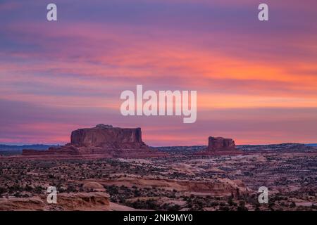 Bunte Sonnenaufgangswolken über dem Monitor und Merrimac Buttes bei Moab, Utah. Stockfoto