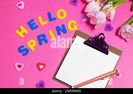 Komposition mit leeren Wörtern Hello Spring und wunderschönen Tulpenblüten auf pinkfarbenem Hintergrund Stockfoto