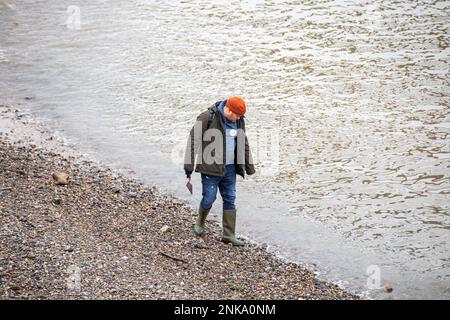 Mudlarker auf der Suche nach interessanten Objekten am felsigen Ufer der Themse bei Ebbe im Londoner Stadtteil Southwark, England Stockfoto