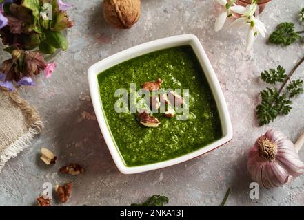 Pesto aus wilden Petersilie-Blättern von Kühen im Frühjahr in einer quadratischen Schüssel mit Walnüssen und Knoblauch Stockfoto