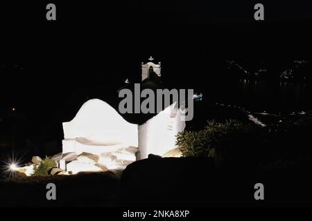 Blick auf eine kleine, beleuchtete, weiß getünchte Kirche in iOS Griechenland auf dem Gipfel des Hügels Stockfoto