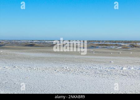 Nahaufnahme des eisigen Meeres, gefrorene Wellen, Felsen und Sonnenblendung auf dem Eis Stockfoto