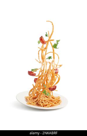 Pasta mit Tomaten und Basilikum, die in einen Teller fallen, Schweben. Stockfoto