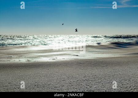 Nahaufnahme des eisigen Meeres, gefrorene Wellen, Felsen und Sonnenblendung auf dem Eis Stockfoto