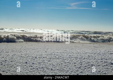 Nahaufnahme des eisigen Meeres, gefrorene Wellen, Felsen und Sonnenblendung auf dem Eis Stockfoto