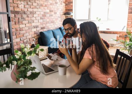 Ernsthafte Ehefrau und Ehemann planen Budget, prüfen Finanzen, fokussierte junge Frau mit Online-Rechner und Zählen von Rechnungen oder Steuern, Mann mit Laptop Stockfoto