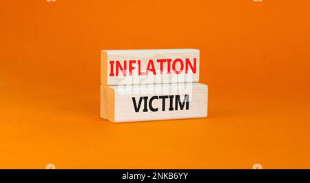 Symbol für Inflationsopfer. Konzeptwörter Inflationsopfer auf Holzblock. Schöner orangefarbener Tischhintergrund. Das Konzept der Inflationsopfer von Unternehmen. Stockfoto