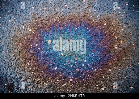 Farbiger Ölfleck auf dem Asphalt. Ein Regenbogenschlick Benzin. Abstrakter Hintergrund. Stockfoto