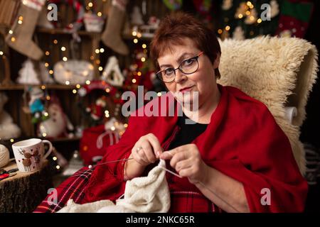 Großmutter näht eine weiche Eule im Weihnachtsgeschäft. Im Studio Stockfoto