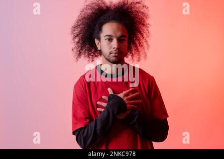 Porträt mit roter LED. Junger Mann mit Afrohaar auf weißem Hintergrund Stockfoto