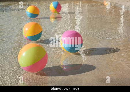 Strandbälle schweben an einem Sommertag im Wasser eines Resortpools. Stockfoto