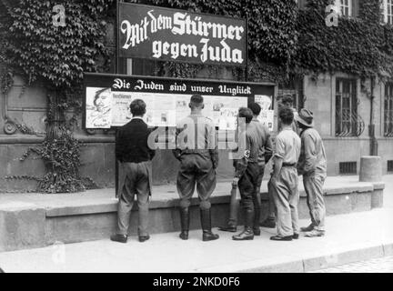 Öffentliche Lektüre von Julius Streichers antisemitischer Zeitung der Stürmer, Worms, 1935. Julius Streicher war ein gewalttätiger antisemitischer Nazi (und im Allgemeinen ein gewalttätiger Mann) und seine tollwütige und hysterische Zeitung die Stürmer hat viel dazu beigetragen, die Flammen des antijüdischen Gefühls im Vorfeld des Krieges zu schüren. Photo Bundesarchiv, Bild 133-075 / Unbekannt / CC-BY-SA 3,0, CC BY-SA 3,0 de, https://commons.wikimedia.org/w/index.php?curid=5338071 Stockfoto