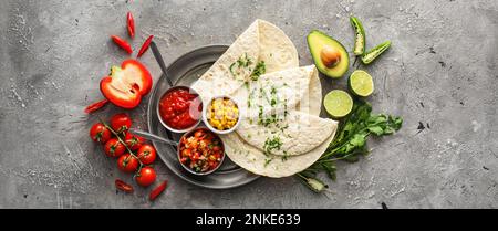 Schüsseln mit leckeren Salsa-Saucen mit Tortilla auf Grunge-Hintergrund, Draufsicht Stockfoto