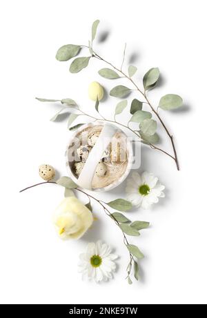 Korb mit Osterwachteleiern, Hähnchen, Kamillenblüten und Eukalyptuszweigen auf weißem Hintergrund Stockfoto