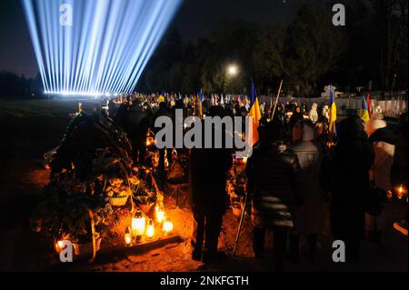 Lemberg, Ukraine. 23. Februar 2023. Die Menschen besuchen die Gräber der gefallenen Soldaten auf dem Friedhof von Lychakiv, wo Hunderte ukrainischer Soldaten, die im letzten Jahr gestorben sind, bei einer Gedenkveranstaltung begraben werden, als symbolische "Strahlen der Erinnerung" auf dem Militärfriedhof von Lychakiv anlässlich des ersten Jahrestages dieses Jahres angezündet wurden Russlands Krieg gegen die Ukraine. Russland marschierte am 24. Februar 2022 in die Ukraine ein und löste damit den größten militärischen Angriff in Europa seit dem Zweiten Weltkrieg aus Kredit: SOPA Images Limited/Alamy Live News Stockfoto