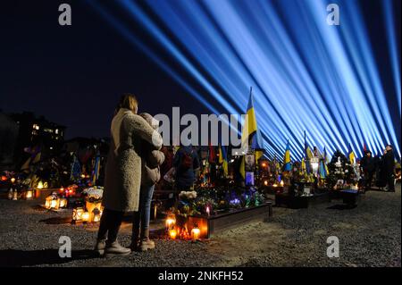 Lemberg, Ukraine. 23. Februar 2023. Familienmitglieder besuchen die Gräber der gefallenen Soldaten auf dem Friedhof Lychakiv, wo Hunderte ukrainischer Soldaten, die im letzten Jahr gestorben sind, bei einer Gedenkveranstaltung begraben werden, als symbolische „Strahlen der Erinnerung“ anlässlich des ersten Jahrestages auf dem Militärfriedhof Lychakiv angezündet wurden Des russischen Krieges gegen die Ukraine. Russland marschierte am 24. Februar 2022 in die Ukraine ein und löste damit den größten militärischen Angriff in Europa seit dem Zweiten Weltkrieg aus (Foto: Mykola Tys/SOPA Images/Sipa USA) Guthaben: SIPA USA/Alamy Live News Stockfoto