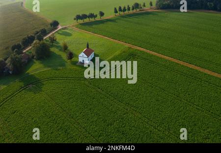 Österreich, Oberösterreich, Reichersberg, Drohnenblick auf Doblkapelle umgeben von grünem landwirtschaftlichem Feld Stockfoto