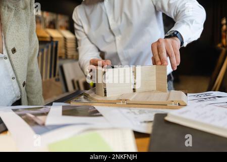 Nahaufnahme eines Mannes, der an einem Holzmodell in der Architektenpraxis arbeitet Stockfoto