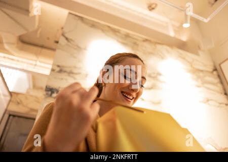 Glückliche Frau, die in die Einkaufstasche schaut Stockfoto
