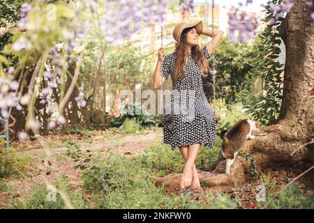 Rücksichtsvolle junge Frau, die im Garten auf der Schaukel schwingt Stockfoto