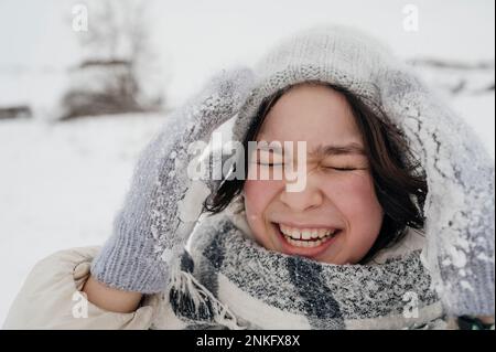 Fröhliches Teenager-Mädchen mit Strickmütze im Winter Stockfoto