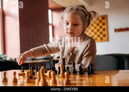 Süßes Mädchen, das Schach im Clubhaus spielt Stockfoto