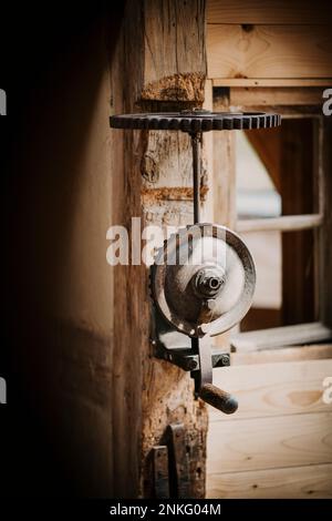 Alte Metallmaschine an Holzwand montiert Stockfoto