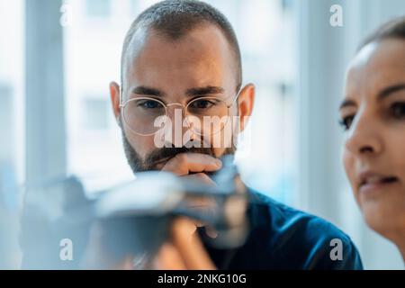 Ein nachdenklicher Geschäftsmann mit einem Kollegen, der im Heimbüro auf die Drohne schaut Stockfoto