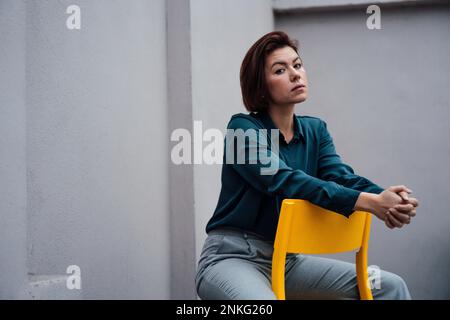 Selbstbewusste junge Geschäftsfrau, die auf einem Stuhl sitzt Stockfoto