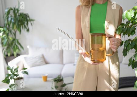 Eine Frau, die zu Hause eine Gießkanne in der Hand hat Stockfoto