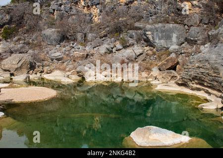 Geologischer Granit, Kalkstein, Felsen und Felsbrocken bilden den Hintergrund für das grüne Wasserbecken im Pedernales Falls State Park Texas Stockfoto