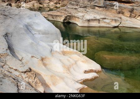 Der sanfte Kalksteinhang im Pedernales Falls State Park Texas, Hill Country, führt in ein grünes Wasserbecken mit einer geologischen Felswand Stockfoto