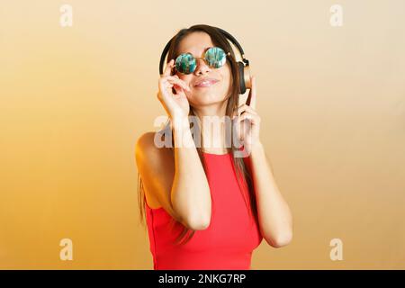 Lächelnde Frau mit Steampunk-Sonnenbrille und Musik über Kopfhörer Stockfoto