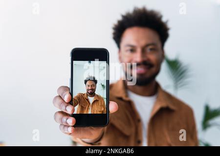 Ein Geschäftsmann, der im Büro ein Selfie mit dem Mobiltelefon macht Stockfoto