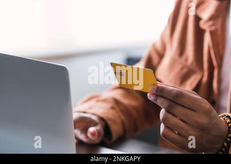 Hand eines Geschäftsmanns mit Kreditkarte am Schreibtisch mit Laptop Stockfoto