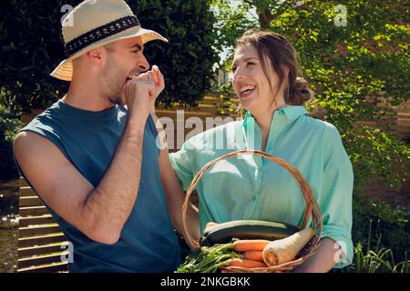 Fröhliches junges Paar, das im Garten Spaß hat Stockfoto
