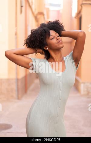 Junge Frau mit Händen im Haar steht vor dem Gebäude Stockfoto