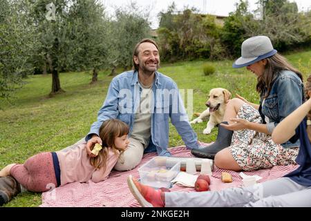 Glückliche Familie, die ein Picknick auf dem Feld macht Stockfoto