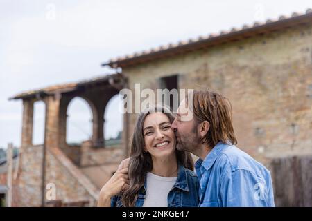 Reifer Mann, der eine Frau vor dem Haus küsst Stockfoto