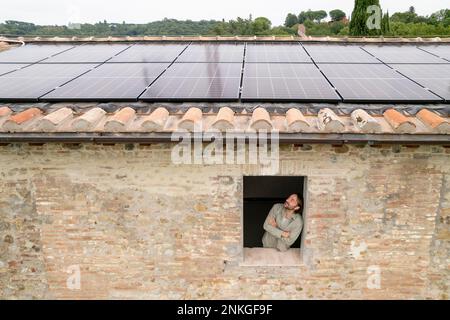 Durchdachter, reifer Mann mit Sonnenkollektoren auf dem Dach Stockfoto