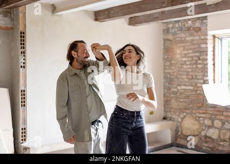 Glücklicher Mann und glückliche Frau tanzen zu Hause zusammen Stockfoto