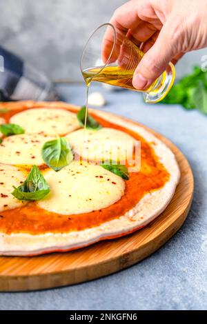 Eine Frau gießt Öl auf Pizza Stockfoto