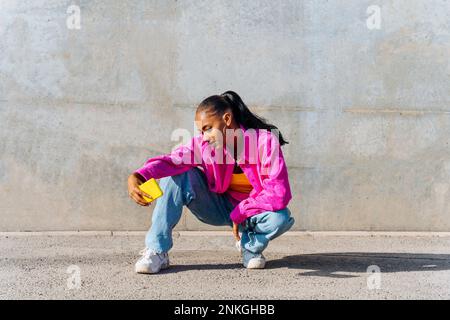 Tänzerin in Hockposition und Selfie über Smartphone an sonnigen Tagen Stockfoto