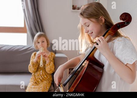 Glückliche Mädchen, die zu Hause Musikinstrumente spielen Stockfoto