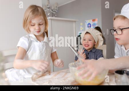 Kinder bereiten Teig mit Mehl in der Küche zu Stockfoto