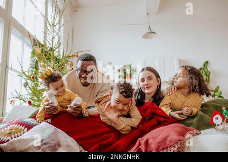 Glückliche Eltern mit Töchtern und Sohn, die sich zu Weihnachten im Wohnzimmer amüsieren Stockfoto