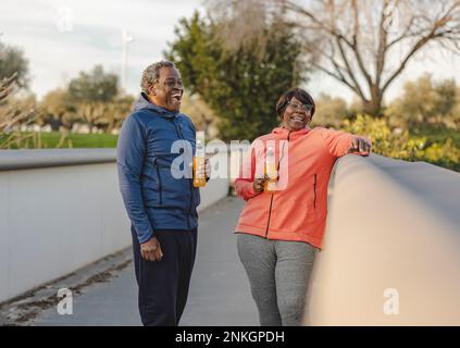 Glückliches Paar mit Energy Drinks, das Spaß am Geländer hat Stockfoto