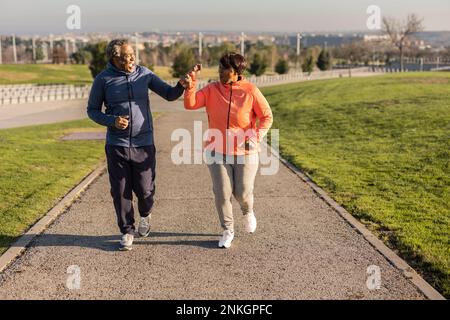 Glückliches Seniorenpaar, das im Park auf dem Fußweg joggt Stockfoto